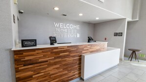 A reception desk with a "Welcome to the Bee Hive State" sign, a "Hilton Honors" sign, and a phone. - Hampton Inn & Suites Salt Lake City Airport (Salt Lake City)