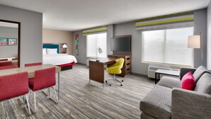 A hotel room with a bed, desk, TV, and seating area. - Hampton Inn & Suites Salt Lake City Airport (Salt Lake City)