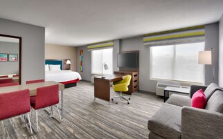Habitación de hotel con cama, escritorio, televisión y zona de estar.