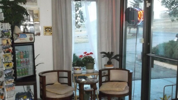 A small cafe with wooden furniture, a Pepsi refrigerator, and a view of the street outside.