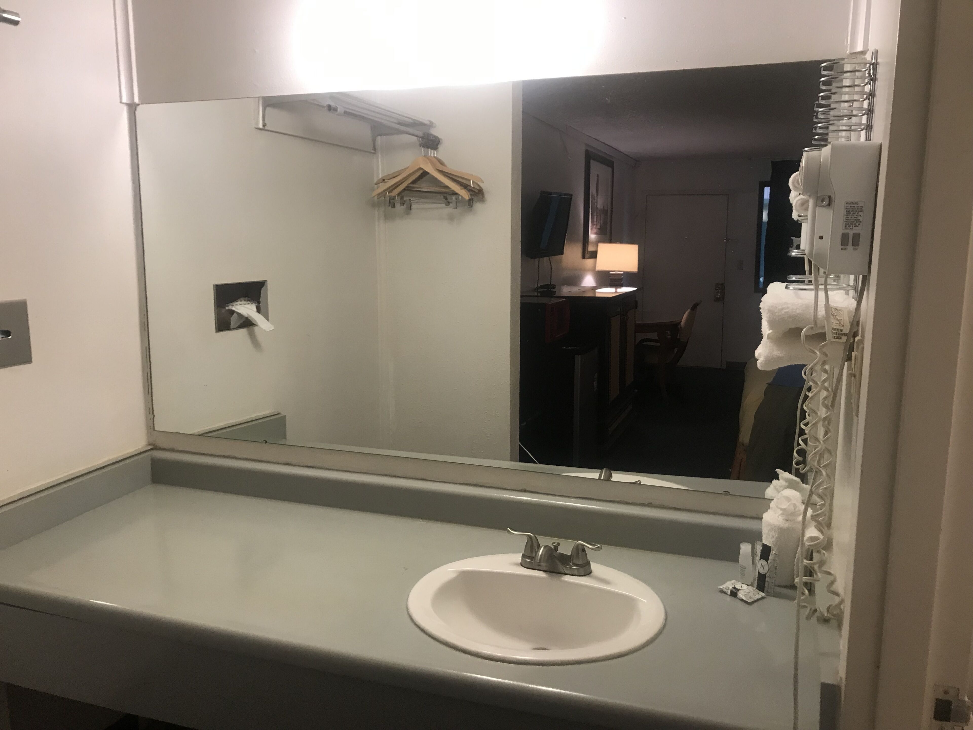 A bathroom with a white sink, a mirror, and a towel rack.