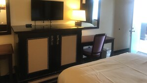 A hotel room with a bed, a desk with a chair, a television, and a mirror.