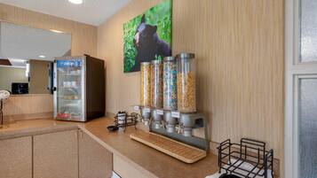 A kitchenette with a refrigerator, a coffee machine, and a cereal dispenser.