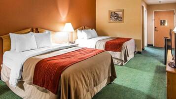 Een hotelkamer met twee bedden, een nachtkastje, een lamp, een schilderij aan de muur en een deur die naar een andere kamer leidt.