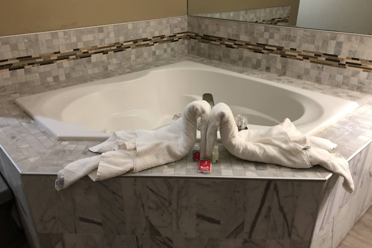 Un baño con una bañera grande, paredes de azulejos y suelo de mármol.