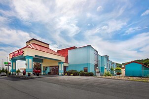 A motel with a red and blue exterior, a gas station in front, and a parking lot.