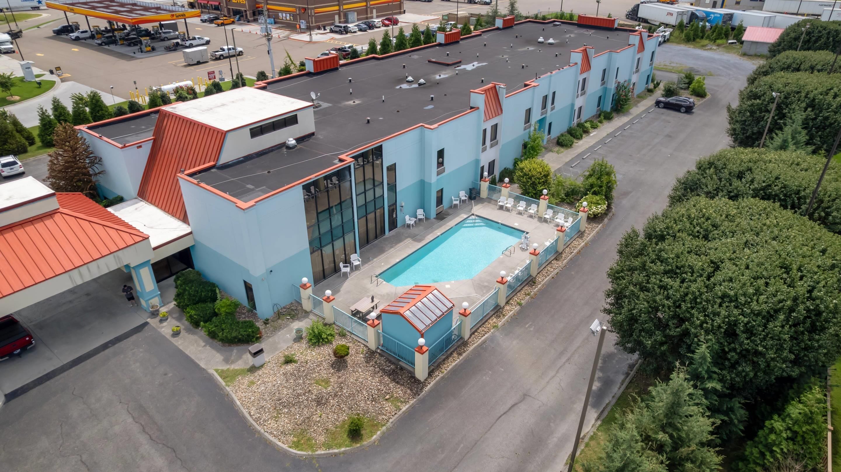Un hotel de varios pisos con piscina en la azotea y aparcamiento.