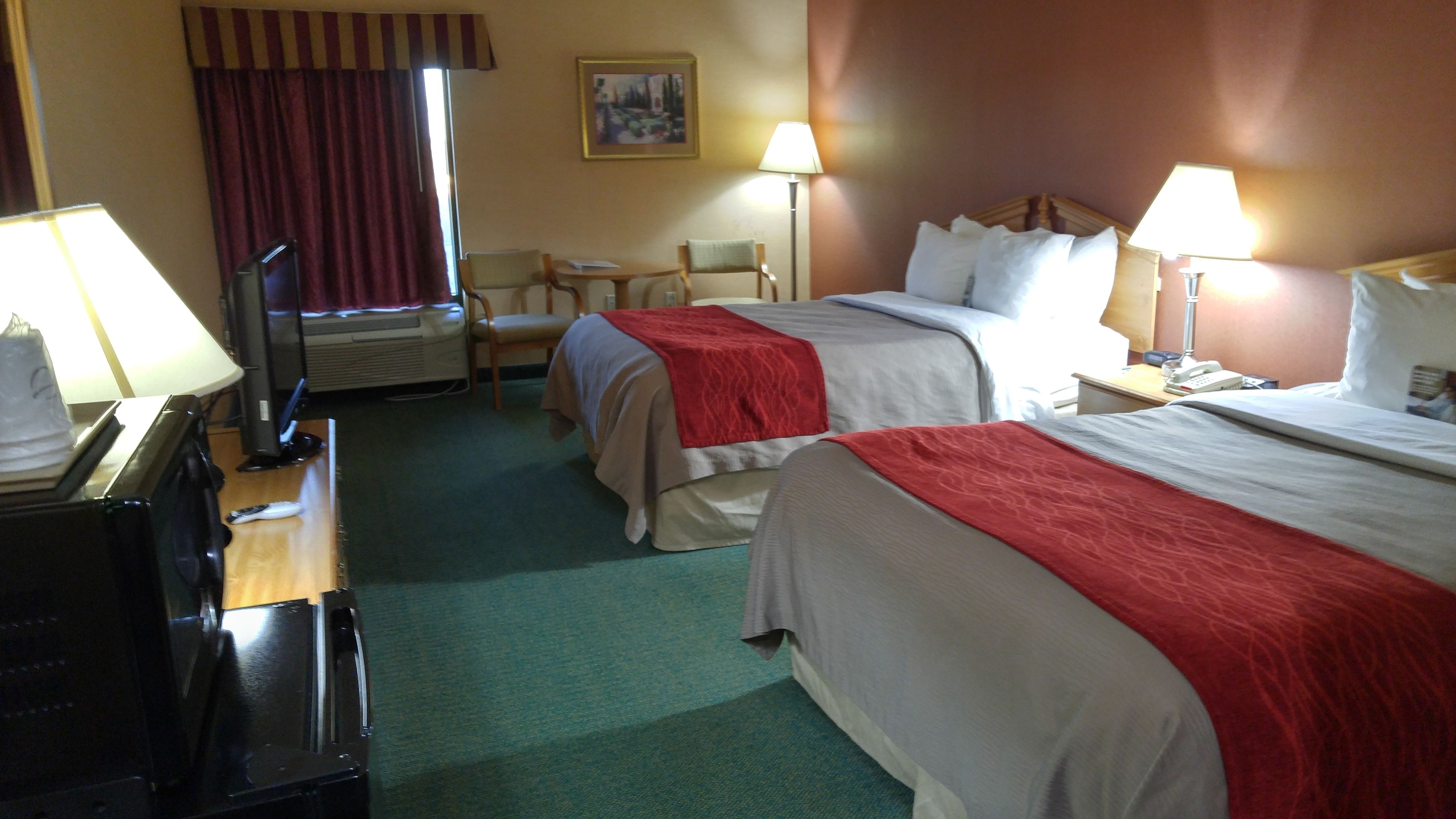 Une chambre d’hôtel avec deux lits, un bureau équipé d’un ordinateur, une chaise et une lampe.