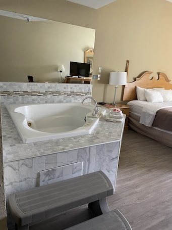 A modern bathroom with a freestanding bathtub, a large mirror, and a wooden headboard bed.