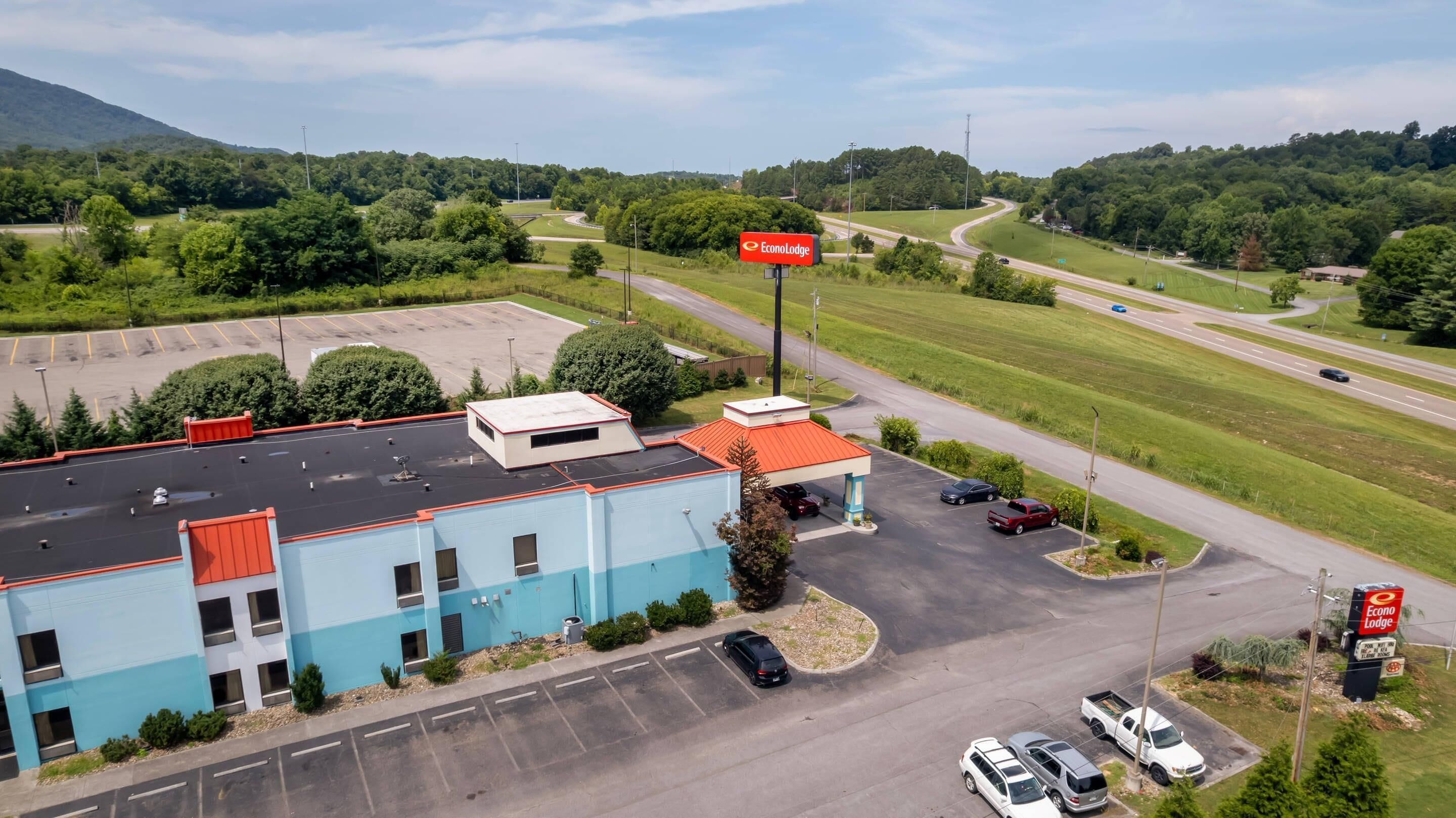 A commercial building with a parking lot, a road with vehicles, and a sign for EconoLodge.