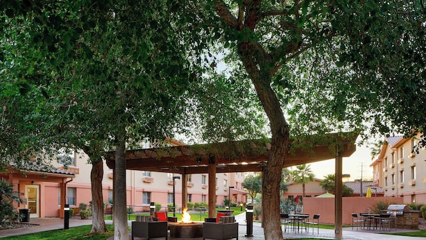 Un patio al aire libre con un brasero, asientos y una pérgola.