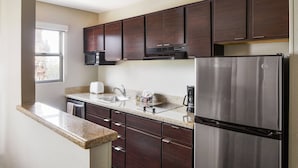 Una cocina moderna con armarios de madera oscura, electrodomésticos de acero inoxidable y encimera de granito.