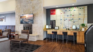 Un vestíbulo con pared de piedra, chimenea, zona de estar, mapa informativo y mostrador de recepción.