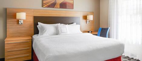 Habitación de hotel con una cama grande, cabecera de madera, dos mesitas de noche y un cuadro en la pared.