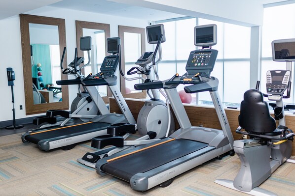 Een sportschool met loopbanden, crosstrainers en een hometrainer.