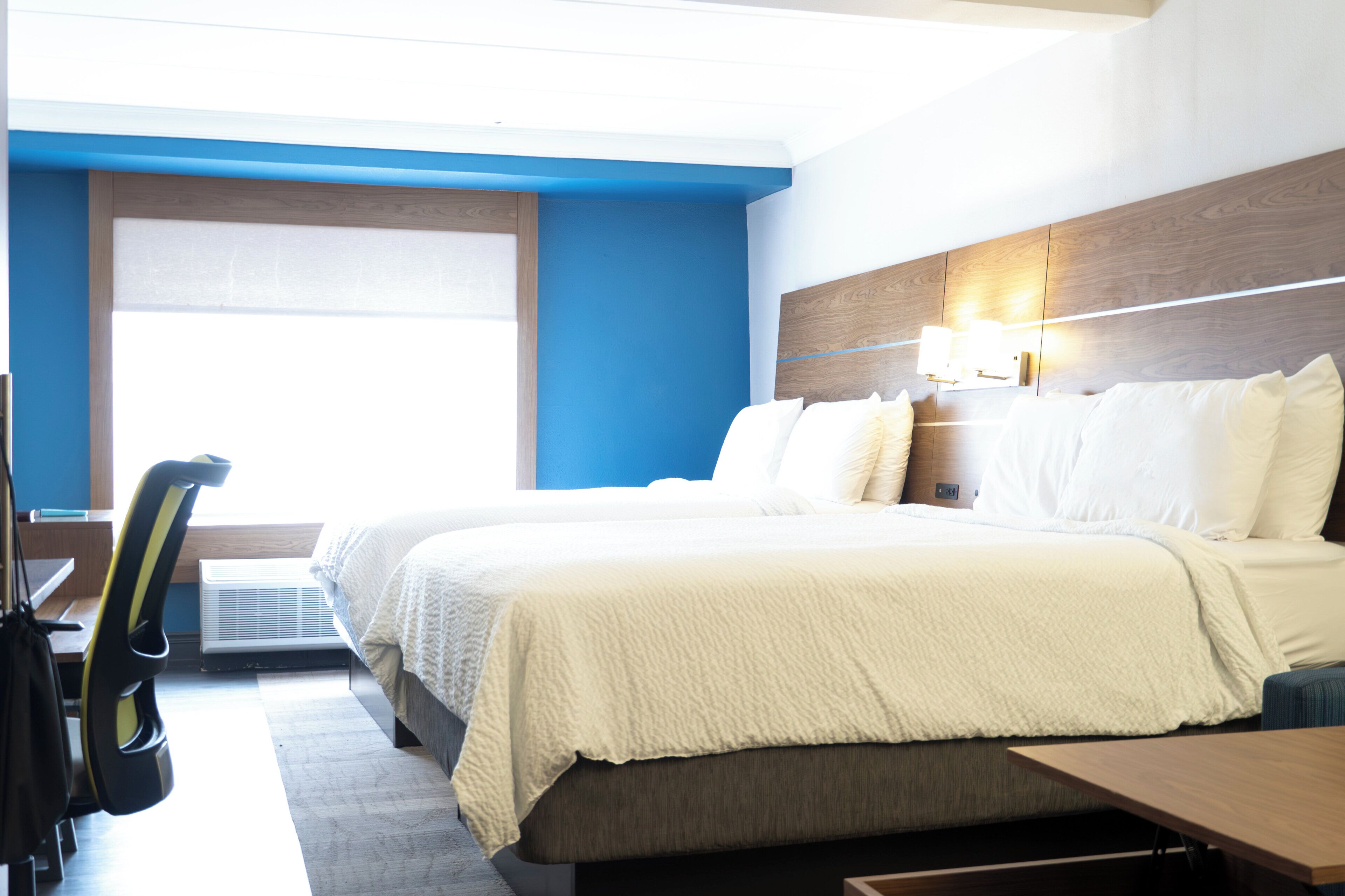 A hotel room with a large bed, a desk, and a chair.