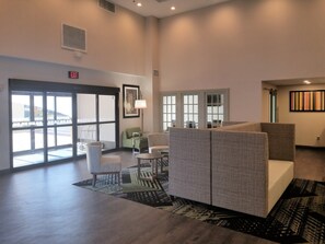 A hotel lobby with seating, a patterned rug, and a large window.