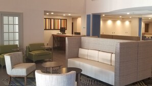 A spacious lobby with a high ceiling, a staircase, and a seating area with a patterned sofa and armchairs. - Holiday Inn Express Columbia NE - Fort Jackson by IHG (Columbia)