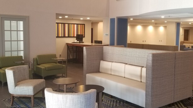 A spacious lobby with a high ceiling, a staircase, and a seating area with a patterned sofa and armchairs. - Holiday Inn Express Columbia NE - Fort Jackson by IHG (Columbia)