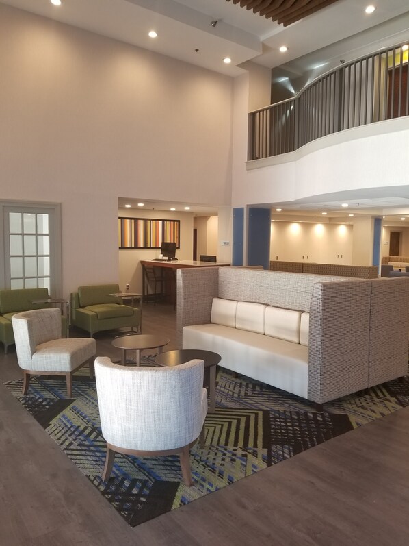 A spacious lobby with a high ceiling, a staircase, and a seating area with a patterned sofa and armchairs. - Holiday Inn Express Columbia NE - Fort Jackson by IHG (Columbia)