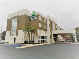 Edificio de Holiday Inn Express con diseño moderno, amplias ventanas y un estacionamiento delantero.