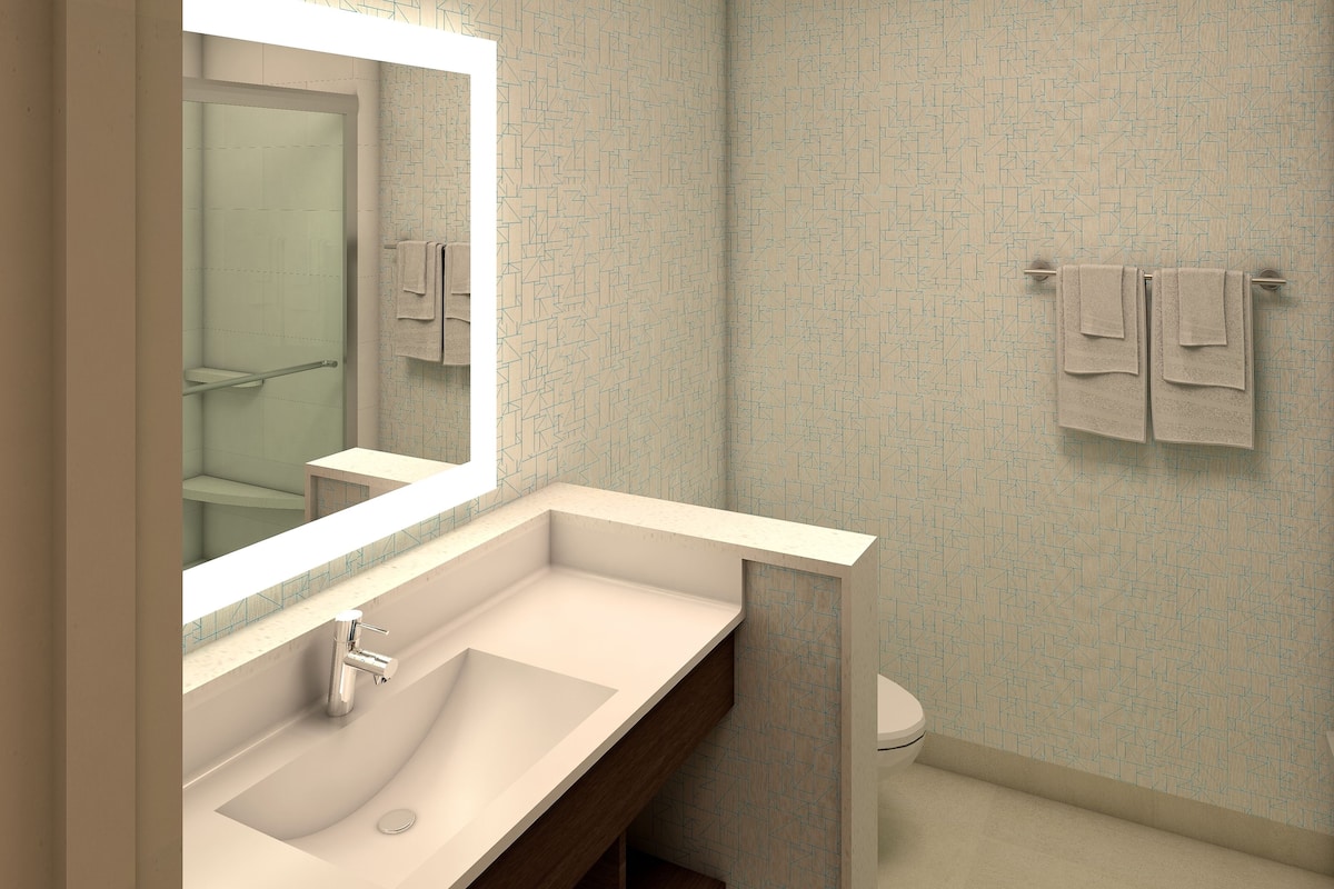 A modern bathroom with a large mirror, a sink, and a toilet.