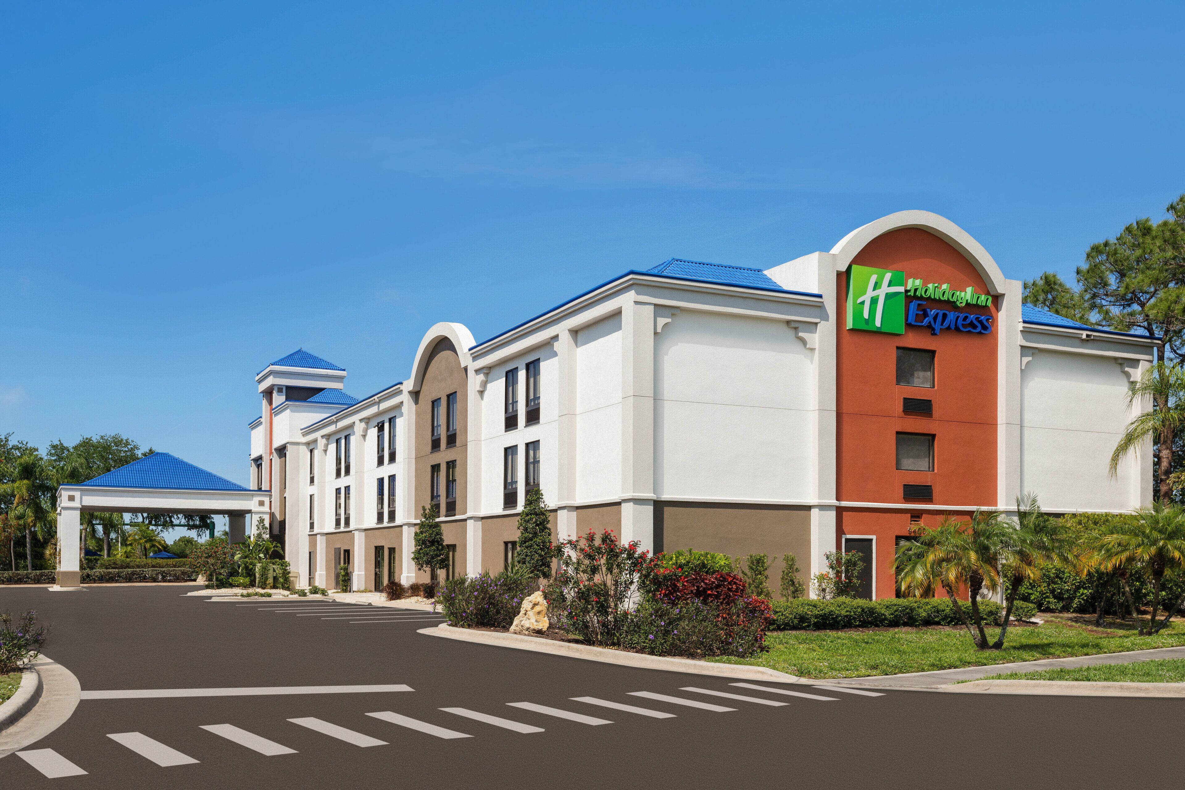 Ein Holiday Inn Express Hotel mit freiem Zugang, einem blauen Dach und einer Beschilderung mit dem Markennamen.