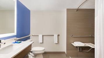 A modern bathroom with a white toilet, a sink with a mirror, and a shower area with a grab bar.