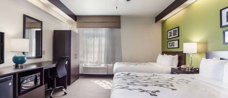 A hotel room with a bed, desk, chair, and a ceiling fan.