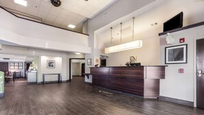 A hotel lobby with a reception desk, framed artwork, a fire alarm, and a staircase leading to an upper level. - Sleep Inn Little River - North Myrtle Beach (Little River)