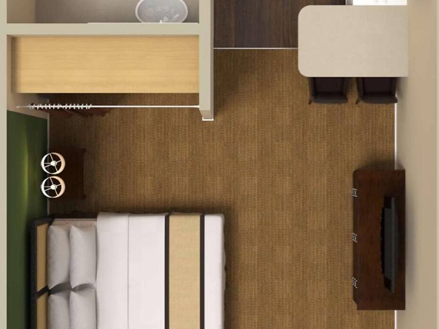 A compact hotel room with a bed, a small desk, a chair, a sofa, a TV, a window, and a bathroom with a bathtub and toilet.