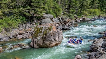 A group of people rafting down a river surrounded by large rocks and dense forest.