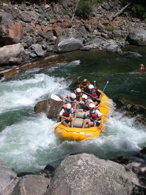 A group of people rafting down a river surrounded by rocks and boulders.