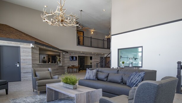 A spacious living area with a grey sofa, a wooden coffee table, and a modern chandelier. - Whitewater Inn (Gallatin Gateway)