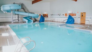 An indoor swimming pool with a blue slide, a staircase, and a lifeguard station. - Whitewater Inn (Gallatin Gateway)