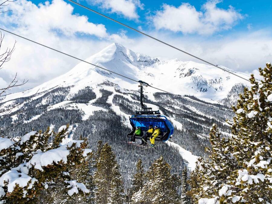 A cable car with skiers ascending a snow-covered mountain.
