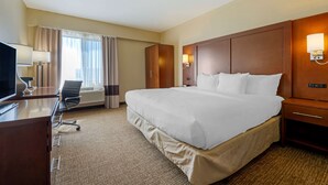 A hotel room with a large bed, a desk with a chair, a television, and a window with curtains. - Comfort Inn Camp Verde I-17 (Camp Verde)