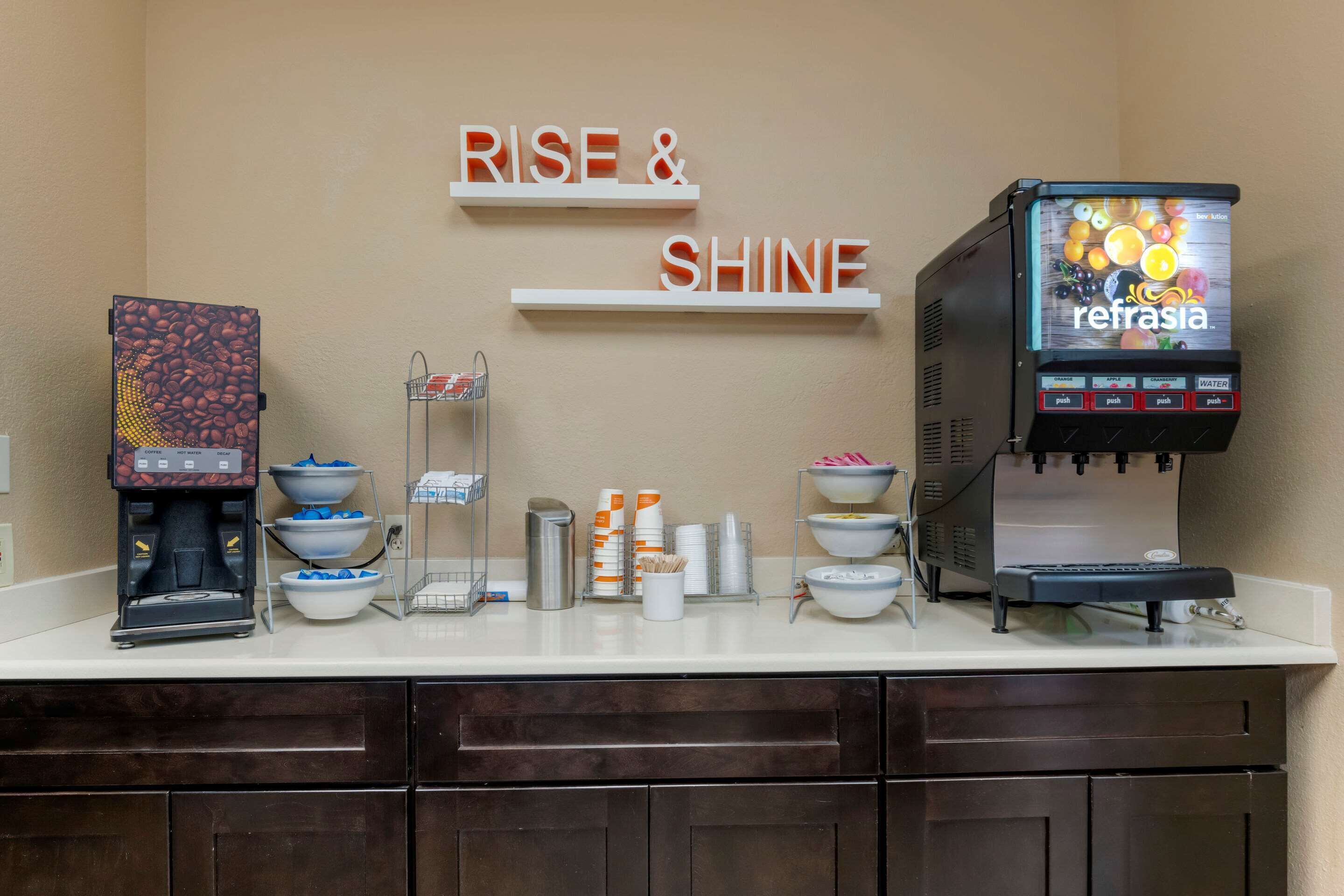 A coffee station with a coffee machine, a water dispenser, and a coffee press. There are bowls and cups on the counter.