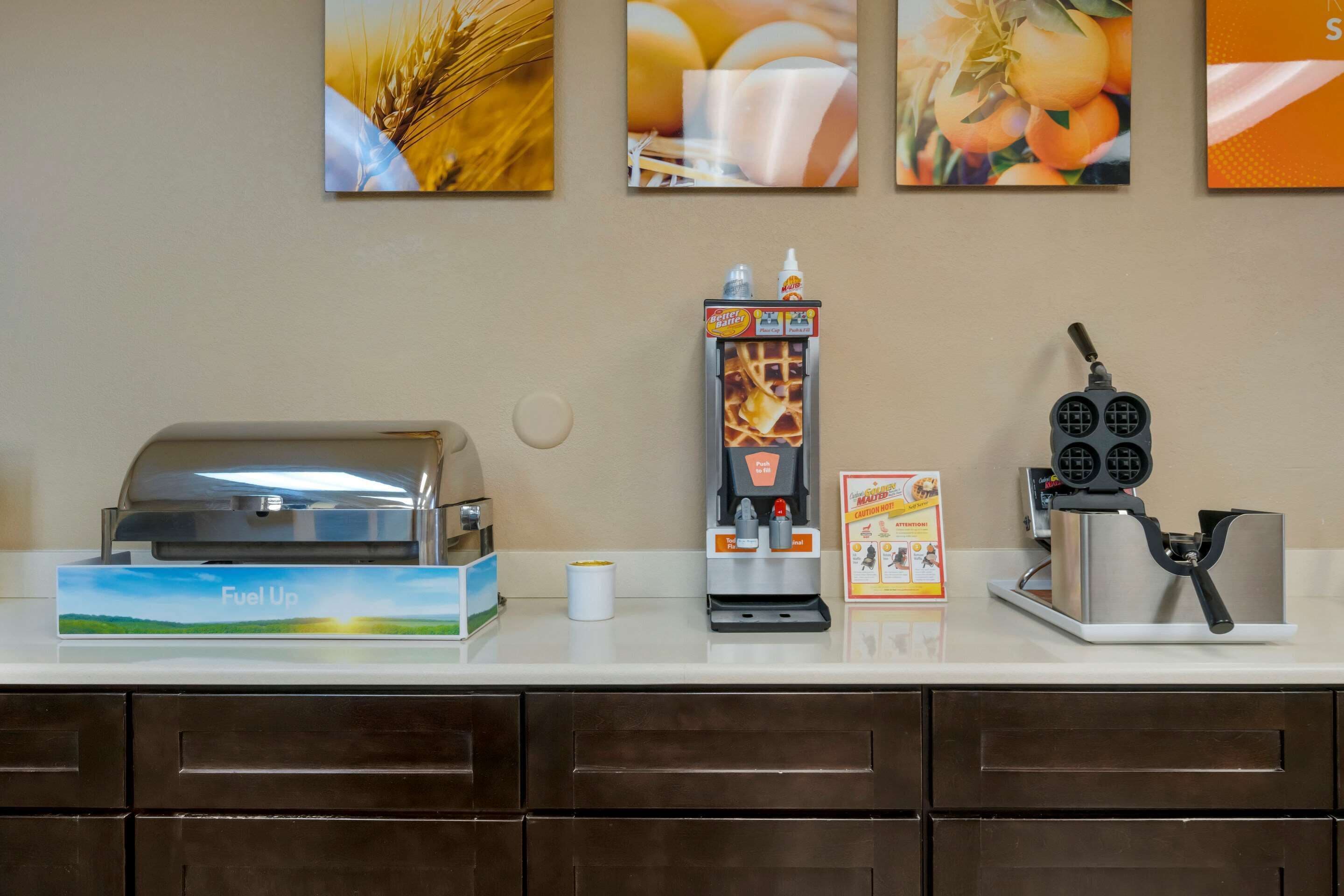 A coffee station with a coffee machine, a waffle maker, and a waffle iron on a counter.