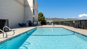 A swimming pool with clear blue water, surrounded by a white building with a flat roof and a view of mountains in the background. - Comfort Inn Camp Verde I-17 (Camp Verde)