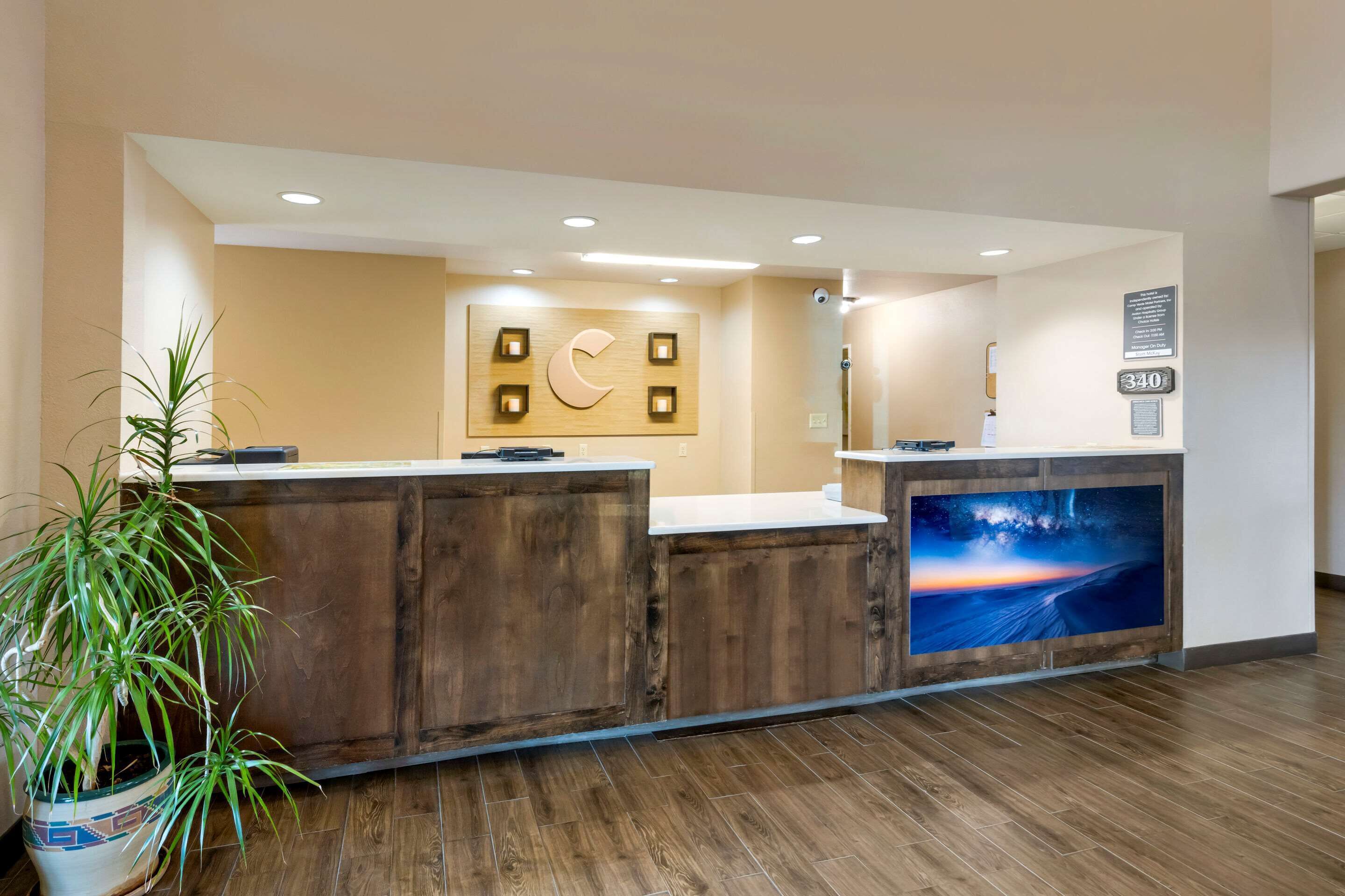 A reception desk with a wooden finish, a large wall-mounted sign with a crescent moon, and a framed picture of a sunset.