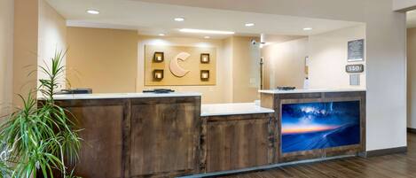 A reception desk with a wooden finish, a large wall-mounted sign with a crescent moon, and a framed picture of a sunset.