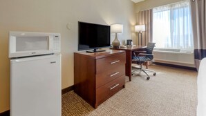 A hotel room with a flat-screen TV, a desk with a lamp, a chair, a microwave, and a mini-fridge. - Comfort Inn Camp Verde I-17 (Camp Verde)