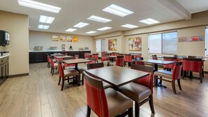 A restaurant with multiple tables and chairs, a kitchen area, and artwork on the walls. - Comfort Inn Camp Verde I-17 (Camp Verde)