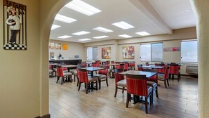A restaurant with multiple tables and chairs, a kitchen area, and large windows. - Comfort Inn Camp Verde I-17 (Camp Verde)