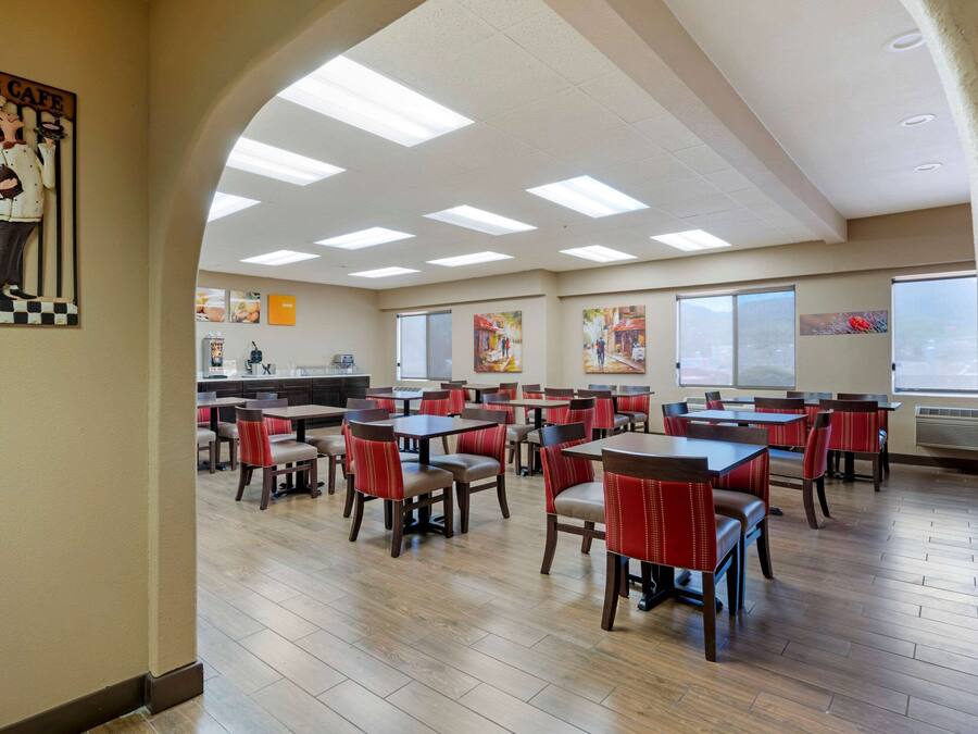 Ein Restaurant mit mehreren Tischen, Stühlen, einer Küche und großen Fenstern.