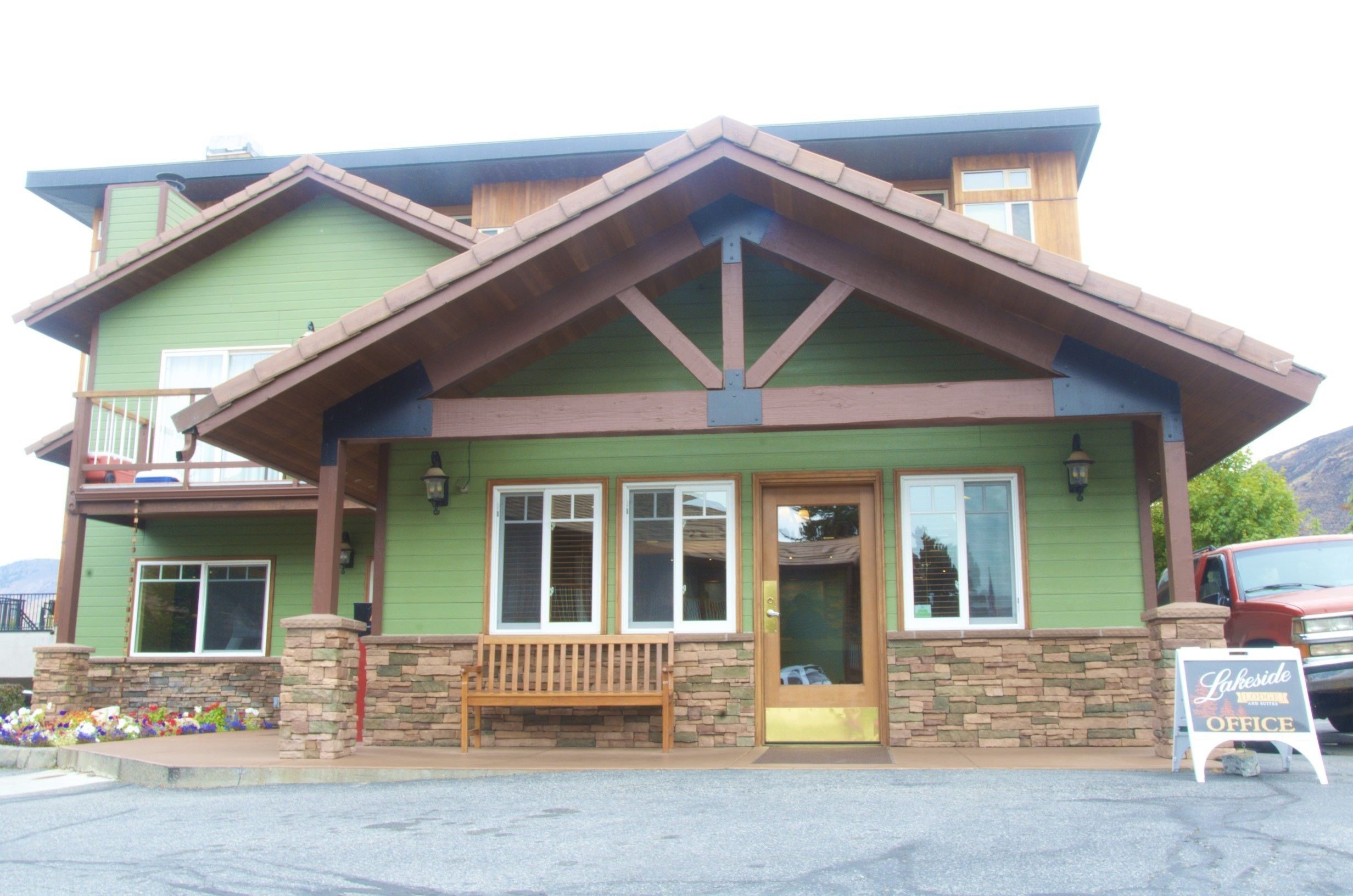 A building with a green exterior, a wooden front porch, and a sign that reads "Lakeside Office."