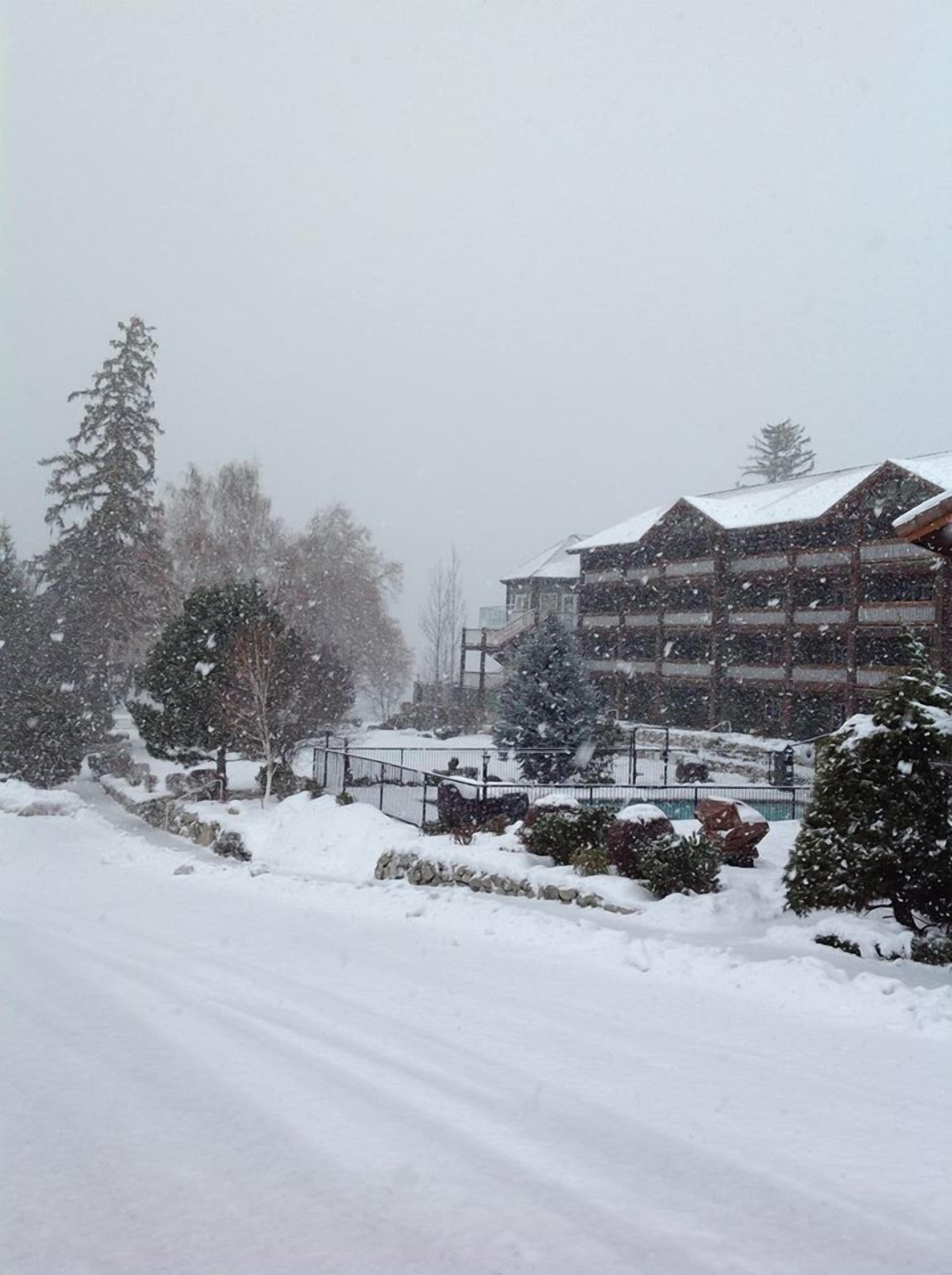 Paisaje nevado con un edificio que tiene varios balcones y un techo cubierto de nieve.