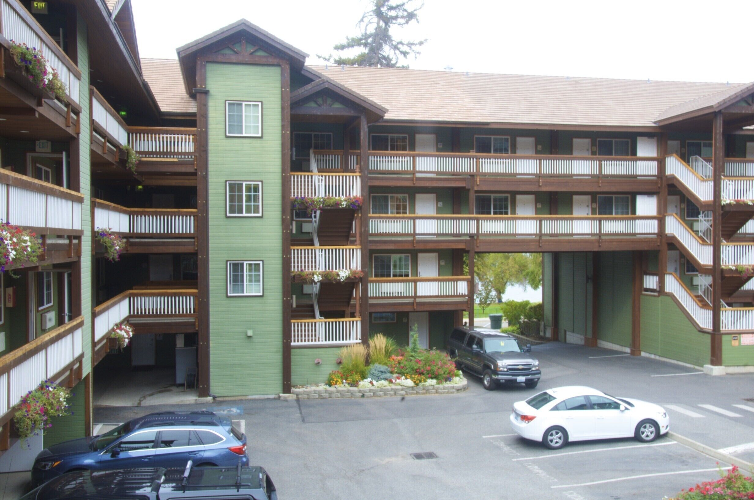 Un hôtel à plusieurs étages doté de balcons, d’un parking et d’une façade verdoyante.