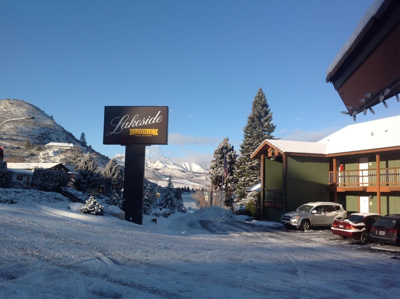 Een sneeuwbedekt landschap met een bordje voor 'Lakeside Lodge and Suites'.